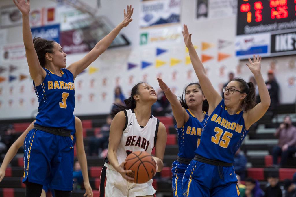 Juneau-Douglas Alyxn Bohulano, center, drives to the basket between Barrows Katelyn Kaleak, left, Lewanne Browerand Sara Wolgemuth, right, at the Princess Cruises Capital City Classic at Juneau-Douglas High School on Friday, Dec. 28, 2018. (Michael Penn | Juneau Empire)