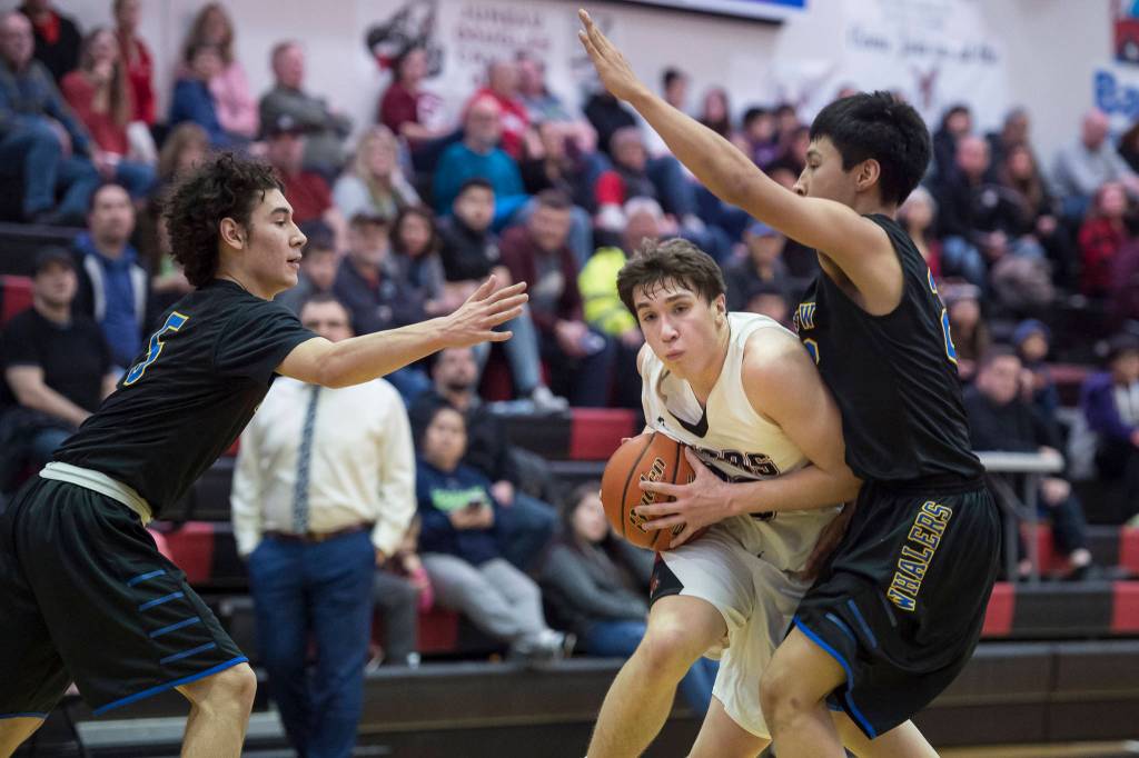 Juneau-Douglas Cooper Kriegmont drives between Barrows Brendon Matthews, left, and Isiah Mongoyak at the Princess Cruises Capital City Classic at Juneau-Douglas High School on Friday, Dec. 28, 2018. Juneau-Douglas won 68-63. (Michael Penn | Juneau Empire)