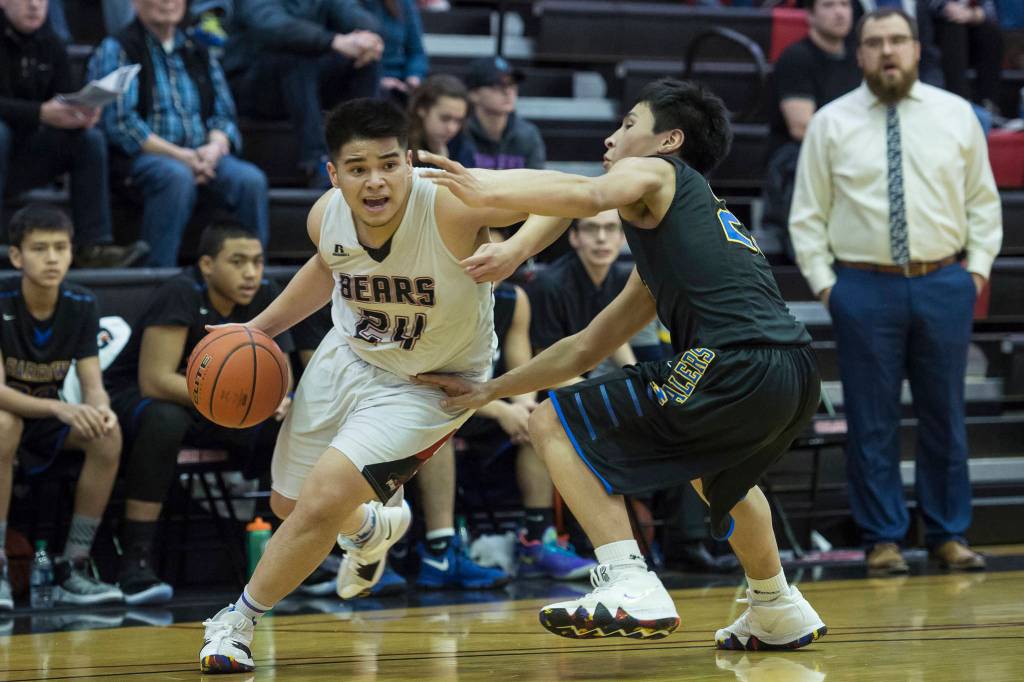 Juneau-Douglas Philip Gonzales, left, drives against Barrows Isiah Mongoyak at the Princess Cruises Capital City Classic at Juneau-Douglas High School on Friday, Dec. 28, 2018. Juneau-Douglas won 68-63. (Michael Penn | Juneau Empire)