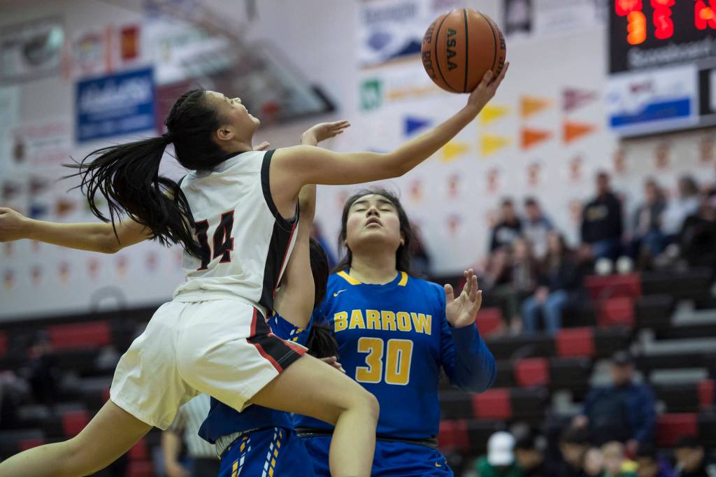 Juneau-Douglas Alyxn Bohulano, left, drives to the basket against Barrows Trinity Manu at the Princess Cruises Capital City Classic at Juneau-Douglas High School on Friday, Dec. 28, 2018. Juneau-Douglas won 66-46. (Michael Penn | Juneau Empire)