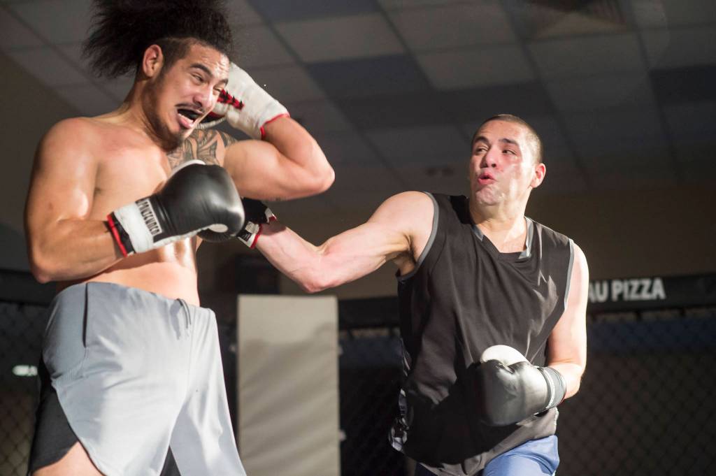 Brian Lauth, right, connects on Fritz Ropati in the main event at the Beatdown 33 at the Elizabeth Peratrovich Hall on Friday, Dec. 28, 2018. Lauth won the match. (Michael Penn | Juneau Empire)