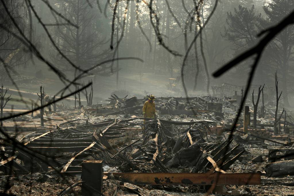 In this Nov. 16, 2018 photo, a firefighter searches for human remains in a trailer park destroyed in the Camp Fire, in Paradise, California. The massive wildfire that killed dozens of people and destroyed thousands of homes has been fully contained after burning for more than two weeks, authorities said Sunday, Nov. 25. (John Locher | Associated Press File)