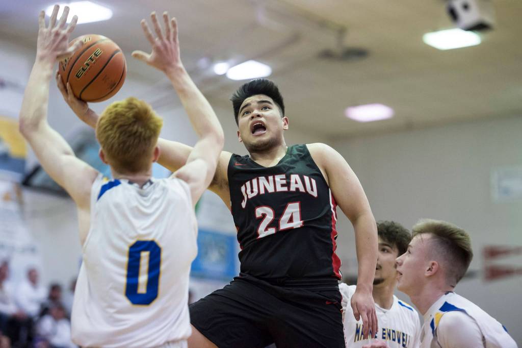 Juneau-Douglas Philip Gonzales, center, lays the ball up in front of Maine-Endwells Gannon Russell, left, at the Princess Cruises Capital City Classic at Juneau-Douglas High School on Saturday, Dec. 29, 2018. Juneau-Douglas won 66-61. (Michael Penn | Juneau Empire)