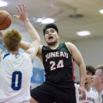 Juneau-Douglas Philip Gonzales, center, lays the ball up in front of Maine-Endwells Gannon Russell, left, at the Princess Cruises Capital City Classic at Juneau-Douglas High School on Saturday, Dec. 29, 2018. Juneau-Douglas won 66-61. (Michael Penn | Juneau Empire)