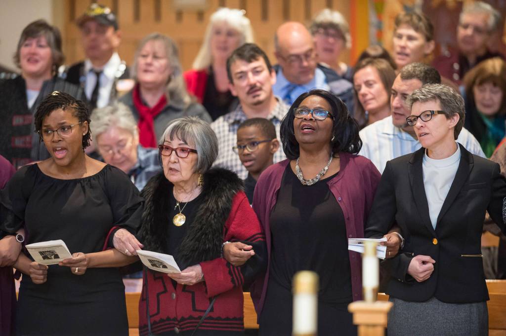 Juneau residents link arms as they sing We Shall Overcome at the Dr. Martin Luther King Jr. 2019 Community Celebration at St. Pauls Catholic Church on Monday, Jan. 21, 2019. In the front row from left are: Latarsha McQueen, of the Black Awareness Association, Dr. Rosita Worl, president of the Sealaska Heritage Institute, Michelle Monts, former president of the Black Awareness Association, and Pastor Tari Stage-Harvey, of the Shepherd of the Valley Lutheran Church. (Michael Penn | Juneau Empire)