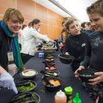 Kari Sellars, marketing manager for NANA Management Services, helps sixth-graders Sage Schultz, right, Jaxon Reis in selecting toppings for their authentic Japanese ramen at Floyd Dryden Middle School as part of Chefs Day on Friday, Jan. 18, 2019. The Anchorage chefs visiting the Juneau and Sitka School Districts to introduced new and healthy foods via performance cooking demonstrations. (Michael Penn | Juneau Empire)