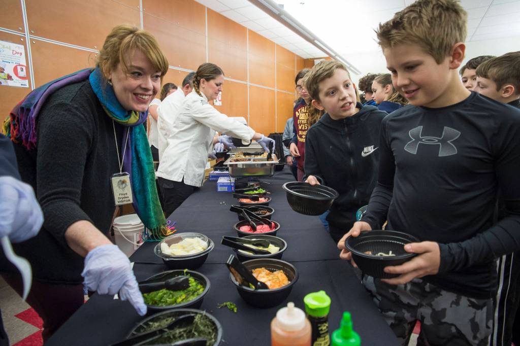 Kari Sellars, marketing manager for NANA Management Services, helps sixth-graders Sage Schultz, right, Jaxon Reis in selecting toppings for their authentic Japanese ramen at Floyd Dryden Middle School as part of Chefs Day on Friday, Jan. 18, 2019. The Anchorage chefs visiting the Juneau and Sitka School Districts to introduced new and healthy foods via performance cooking demonstrations. (Michael Penn | Juneau Empire)