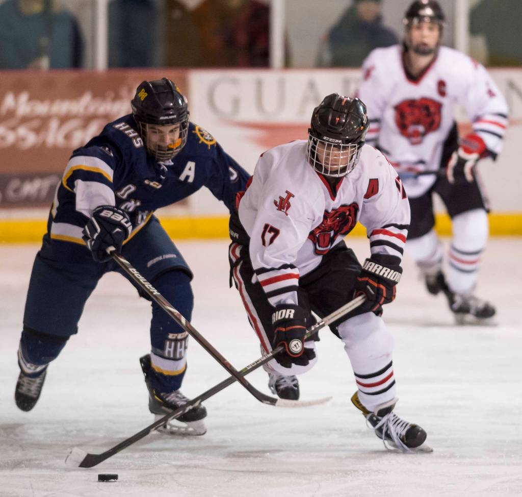 Juneau-Douglas Bill Bosse, right, moves the puck against Homers Ethan Pitzman at Treadwell Arena on Friday, Jan. 18, 2019. JDHS won 4-3 in overtime. (Michael Penn | Juneau Empire)