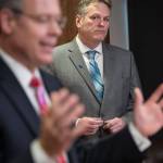 Commissioner Designee Bruce Tangeman presents bills to pay residents cut PFD funds as Gov. Mike Dunleavy watches during a press conference at the Capitol on Wednesday, Jan. 16, 2019. (Michael Penn | Juneau Empire)