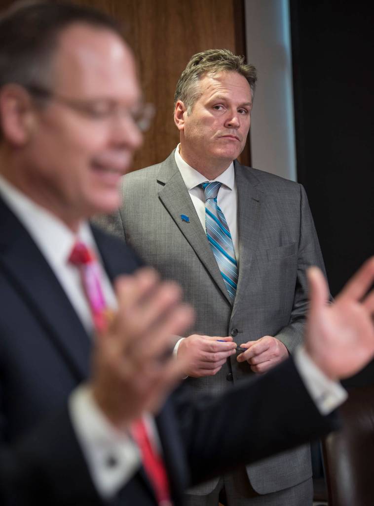 Commissioner Designee Bruce Tangeman presents bills to pay residents cut PFD funds as Gov. Mike Dunleavy watches during a press conference at the Capitol on Wednesday, Jan. 16, 2019. (Michael Penn | Juneau Empire)