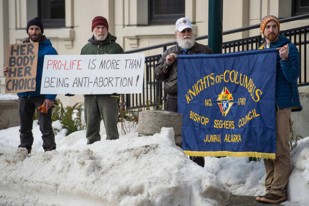 Paul Desloover, second from left, and his son, Dan, left, hold a counter protest as Leo DeMeo and Andrew Klausner, of the Knights of Columbus attend the Alaskans for Life, Inc. annual Rally for Life in front of the Capitol on Tuesday, Jan. 22, 2019. (Michael Penn | Juneau Empire)
