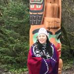 Tlingit artist Alison Marks stands in regalia next to a totem pole she carved. The pole was recently raised in Yakutat. (Courtesy Photo | Thom Landgreen)
