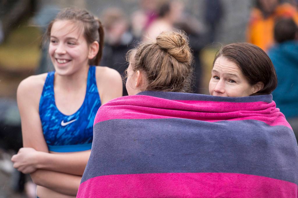 Cindy Tuckwood, right, huttles behind a towel with her daughter Skylar, 14, and friend Mila Hardgrave, 12, before taking to the frigid waters at Auke Bay Recreation Area for the annual Juneau Polar Bear Dip on Tuesday, Jan. 1, 2019. Nearly 200 people took the plunge to start off the new year. (Michael Penn | Juneau Empire)