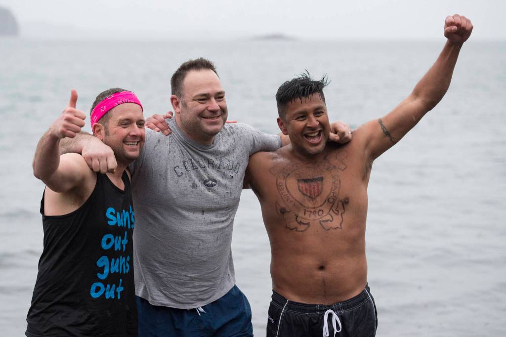U.S. Coast Guard members John Dale, left, Chris Coutu, center, and Marvin Pena pose for a picture before taking to the frigid waters at Auke Bay Recreation Area for the annual Juneau Polar Bear Dip on Tuesday, Jan. 1, 2019. Nearly 200 people took the plunge to start off the new year. (Michael Penn | Juneau Empire)