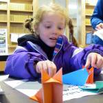 Wren Mesdag, 4, finishes up an origami whale during the Family Fair Friday, Jan.4, 2019. One of the stations at the event allowed children to fold paper into shapes resembling Alaskan animals. (Ben Hohenstatt | Capital City Weekly)