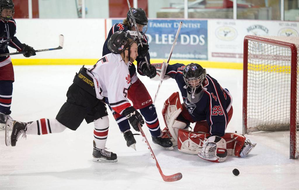Juneau-Douglas Cully Corrigan scores on North Poles goalie Moses Halbert as his helmet is knocked away by North Poles Jeff Doty at Treadwell Arena on Friday, Jan. 19, 2018.