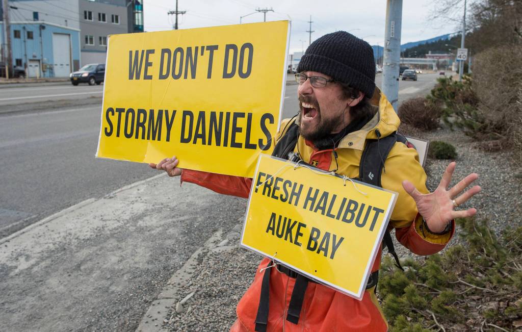 Caven Pfeiffer, of Sitka, waves signs at the corner of Egan Drive and 10th Street on Monday, April 2, 2018, to bring attention to him selling halibut off his fishing boat, Sword, at the Don Statter Memorial Boat Harbor in Auke Bay. He is selling his fish for $9.50 per pound. Pfeiffer said,  We have a  poor price this year. We got a 15 percent cut in our quota and then our price is about 30 percent less. Thats why I am working so hard. One side of his sign reads We dont do Stormy Daniels. The other side reads We do Stormy Seas. Pfeiffer said he just wanted to have a little fun while selling his fish.
