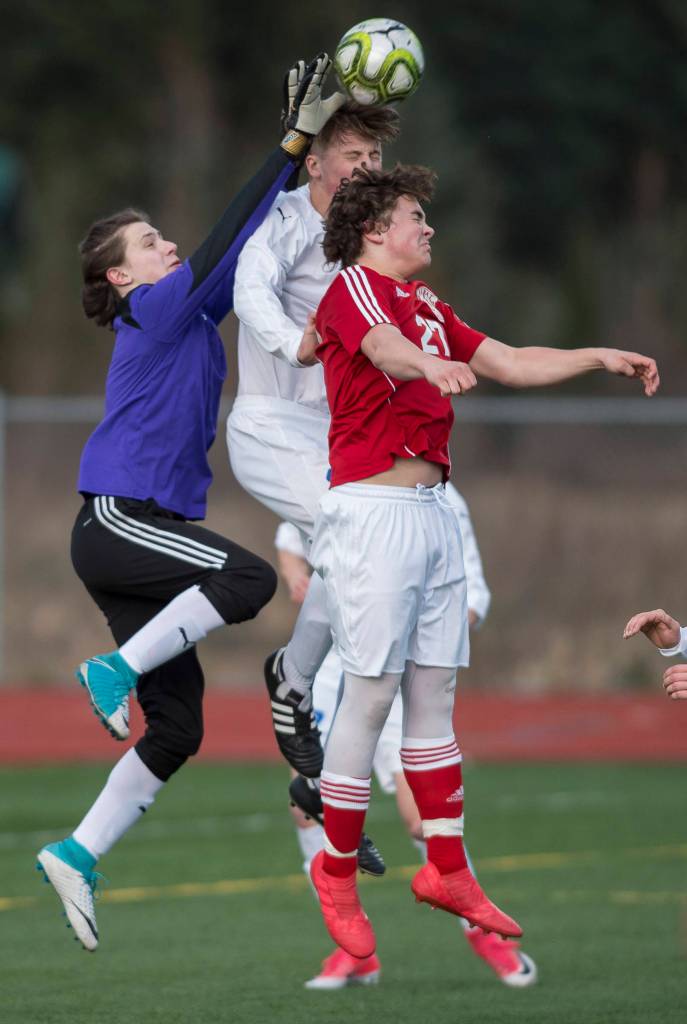Thunder Mountains goalkeeper Alan Plosay, left, and teammate Kieran Kollar, center, knock the ball away from Kenais Nathaniel Beiser at THMS on Friday, April 20, 2018.