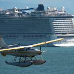 A Wings Airways floatplane takes off from Juneaus downtown harbor as the Norwegian Bliss leaves it port of call on Tuesday, July 31, 2018. (Michael Penn | Juneau Empire)