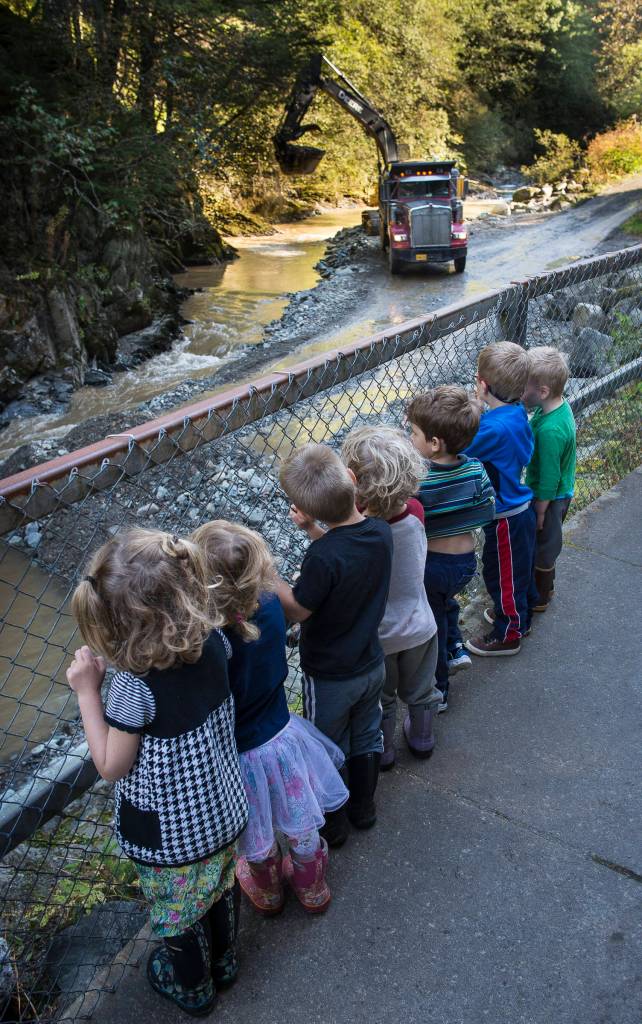 Children attending Fiddleheads Preschool line up along the fence at Cope Park to watch an excavator dredge Gold Creek on Wednesday, Sept. 12, 2018. (Michael Penn | Juneau Empire)