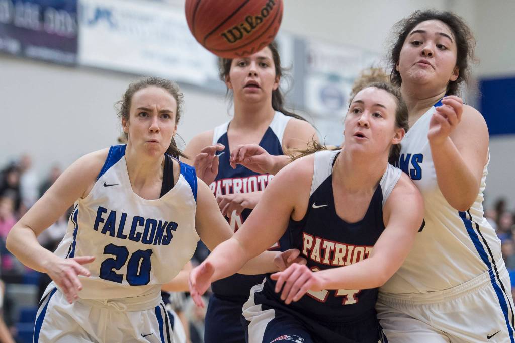 Thunder Mountains Iayanah Brewer, left, and teammate Tasi Fenumiai, right, battle for the ball against North Poles Alex Hodal, front, and Claire Richmond at TMHS on Thursday, Dec. 13, 2018. TMHS won 57-39. (Michael Penn | Juneau Empire)