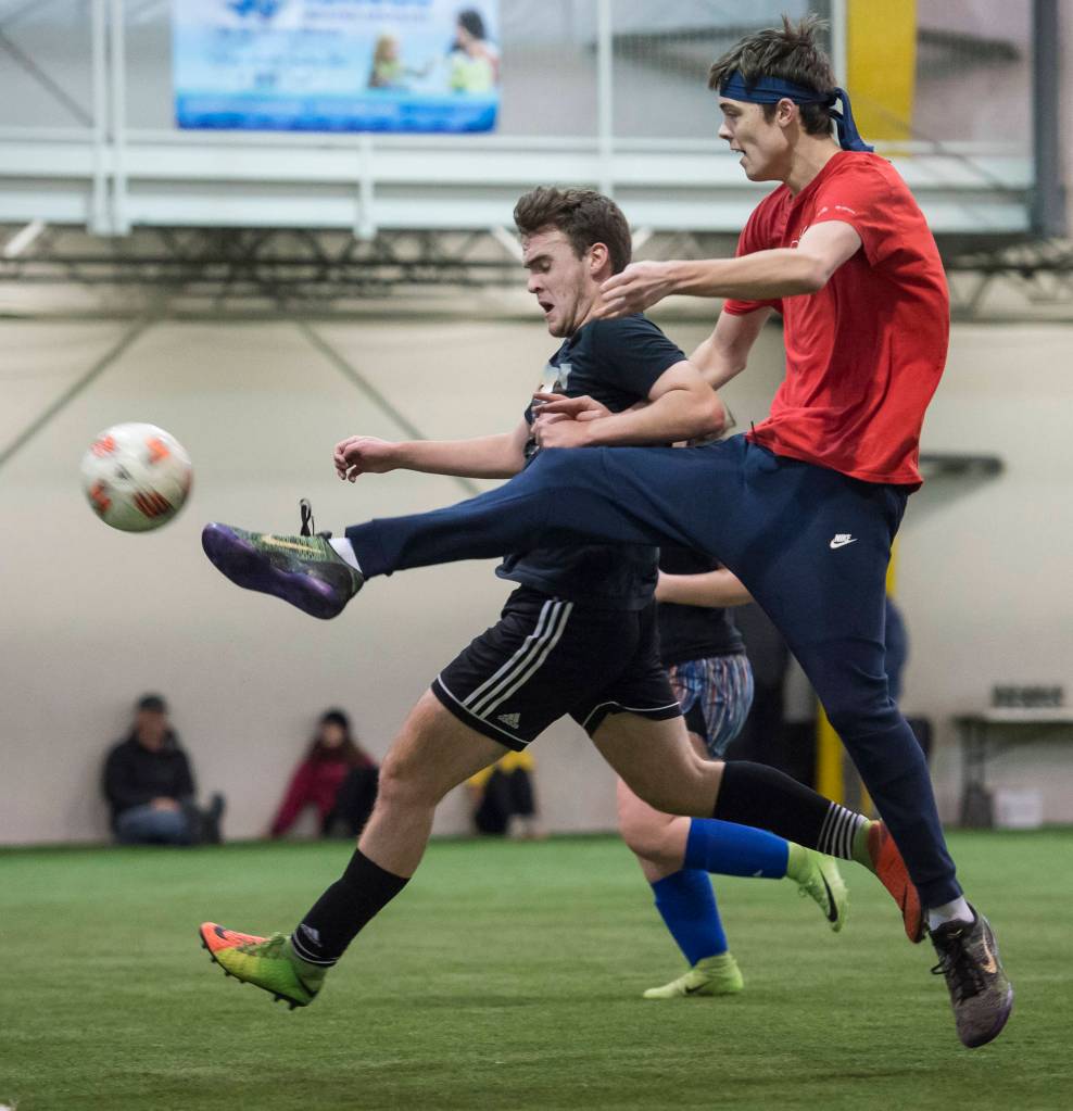 Grinch Gangs Kaleb Tompkins, right, fires a shot to the goal against Black Ices Michael White in the finals of the senior division at the annual Holiday Cup Soccer Tournament at the Wells Fargo Dimond Park Field House on Monday, Dec. 31, 2018. The Grinch Gang won 8-2. (Michael Penn | Juneau Empire)