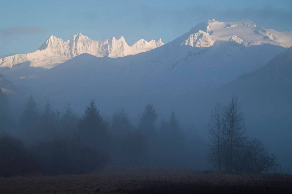 The Mendenhall Towers light up during sunrise as fog rolls off the Mendenhall River on Thursday, Jan. 3, 2019. (Michael Penn | Juneau Empire)