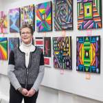 Carol Carlson stands with her paintings on display at the Juneau Arts & Humanities Council during First Friday on Friday, Jan. 4, 2019. (Michael Penn | Juneau Empire)