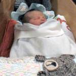 Yakutat residents Cody Kunau and Samantha Munoz sit with their baby Saige Roisin Kuneau on Friday, Jan. 4 at Bartlett Regional Hospital. Saige was the first baby born at the hospital this year, and received a boat carved by BRH Emergency Room Dr. Lindy Jones. (Alex McCarthy | Juneau Empire)