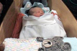 Yakutat residents Cody Kunau and Samantha Munoz sit with their baby Saige Roisin Kuneau on Friday, Jan. 4 at Bartlett Regional Hospital. Saige was the first baby born at the hospital this year, and received a boat carved by BRH Emergency Room Dr. Lindy Jones. (Alex McCarthy | Juneau Empire)