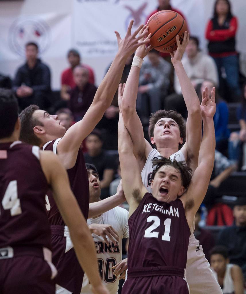 Juneau-Douglas Garrett Bryant rebounds against Ketchikans Jake Taylor, left, and Kristian Pihl at JDHS on Friday, Jan. 11, 2019. JDHS won 75-67. (Michael Penn | Juneau Empire)
