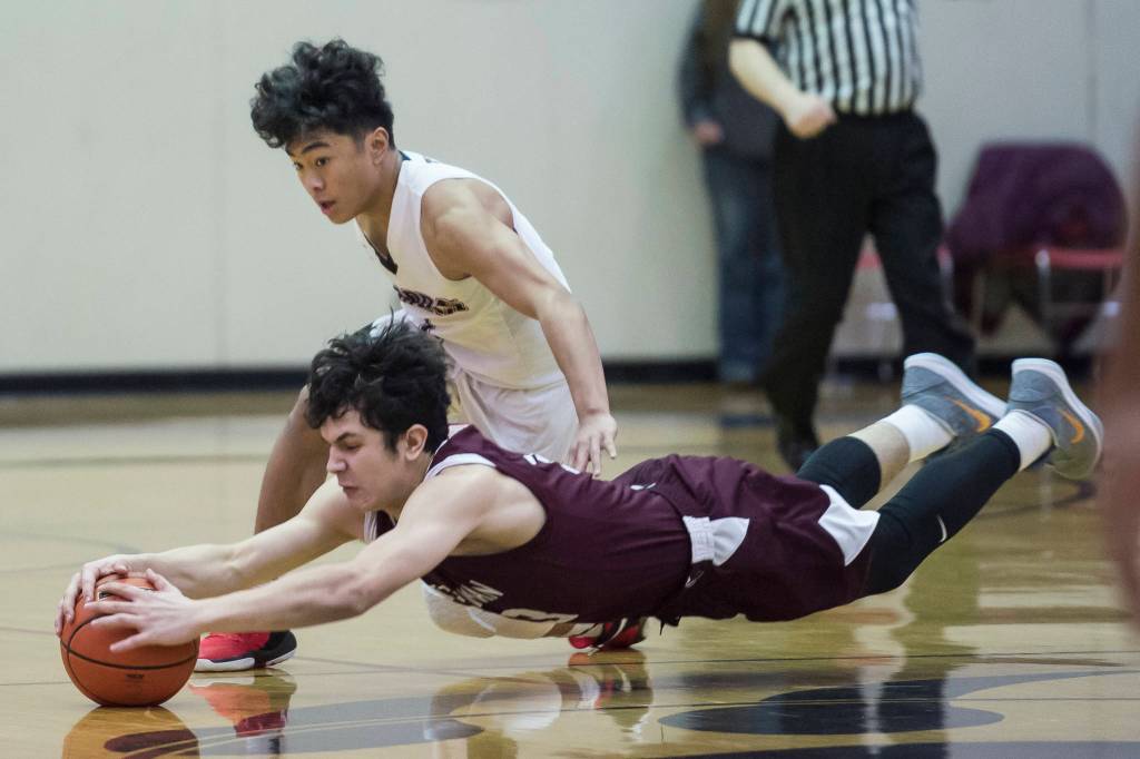 Ketchikans James Nordlund dives for the ball against Juneau-Douglas Israel Yadao at JDHS on Friday, Jan. 11, 2019. JDHS won 75-67. (Michael Penn | Juneau Empire)