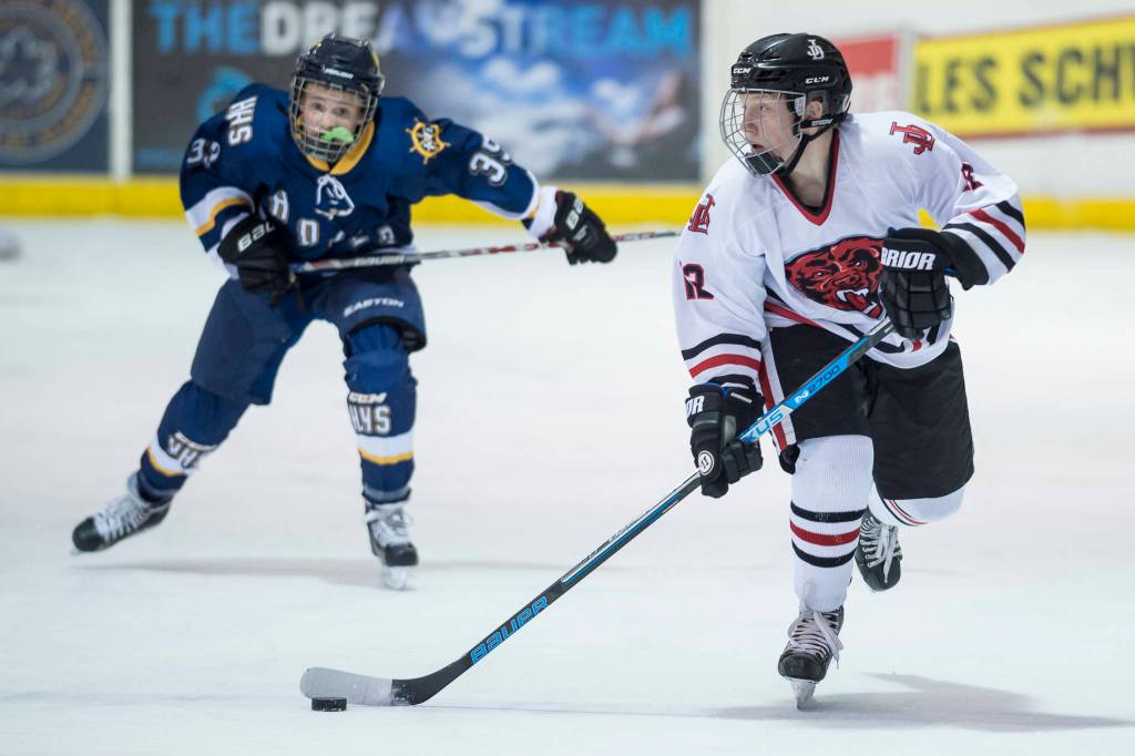 Juneau-Douglas Kyler Alderfer, right, moves the puck in front of Homers Casey Otis at Treadwell Arena on Friday, Jan. 18, 2019. JDHS won 4-3 in overtime. (Michael Penn | Juneau Empire)