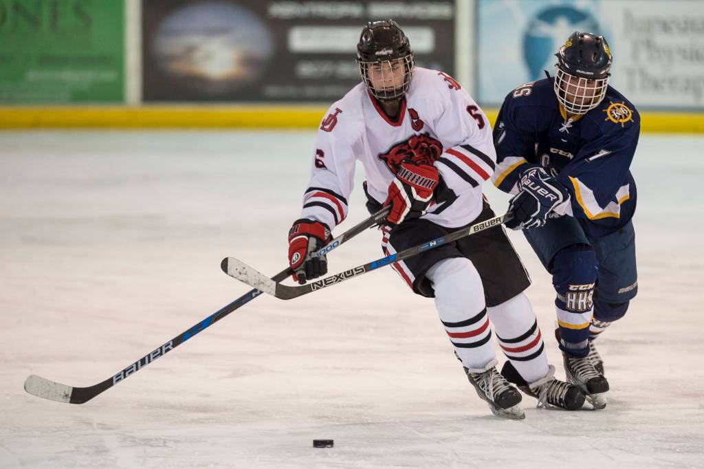 Juneau-Douglas Cameron Smith drives against Homers Tyler Gilliland at Treadwell Arena on Friday, Jan. 18, 2019. JDHS won 4-3 in overtime. (Michael Penn | Juneau Empire)