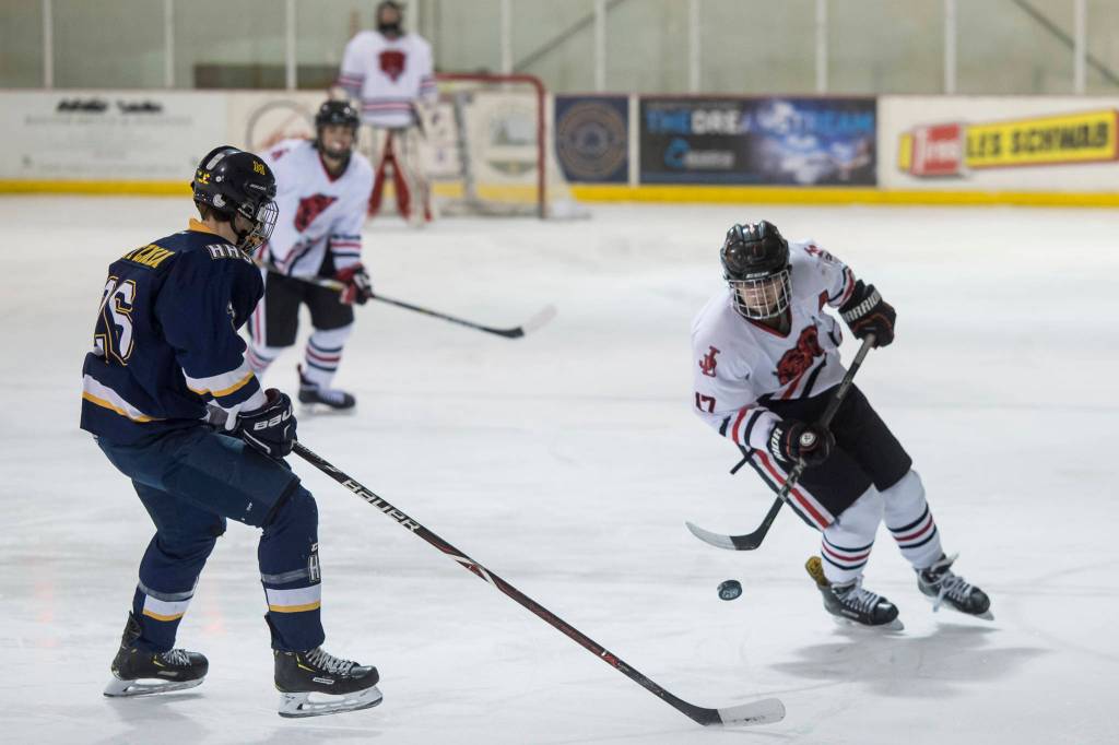 Juneau-Douglas Bill Bosse, right, moves the puck against Homers Ethan Pitzman at Treadwell Arena on Friday, Jan. 18, 2019. JDHS won 4-3 in overtime. (Michael Penn | Juneau Empire)