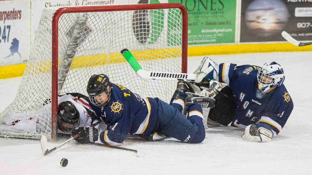 Juneau-Douglas Dalton Hoy crashes into the net as he competes against Homers Tucker Weston, center, and goalie Hunter Warren at Treadwell Arena on Friday, Jan. 18, 2019. JDHS won 4-3 in overtime. (Michael Penn | Juneau Empire)