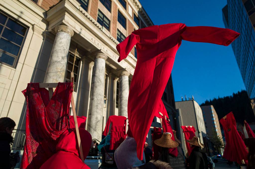 Native women hold up red dresses to symbolize missing and murdered indigenous women during the Womens March on Juneau in front of the Alaska State Capitol on Saturday, Jan. 19, 2019. (Michael Penn | Juneau Empire)