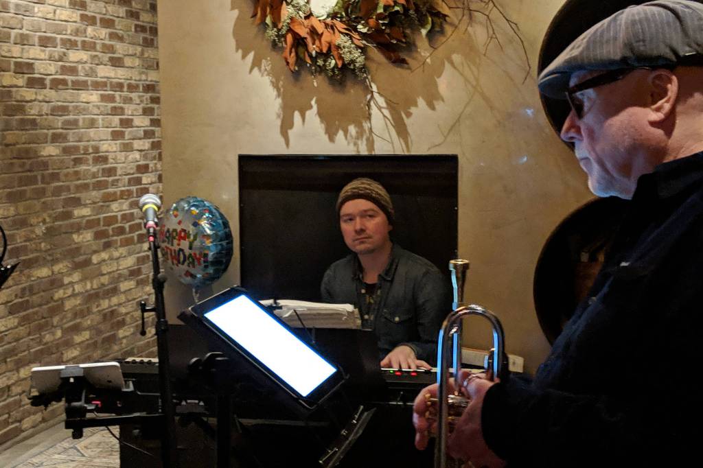 Luke Weld sits behind his keyboard and Greg Kalbaugh readies to play trumpet before the Juneau Fives regular Thursday Night Jazz show at the Narrows Bar, Jan. 31, 2019. (Ben Hohenstatt | Juneau Empire)