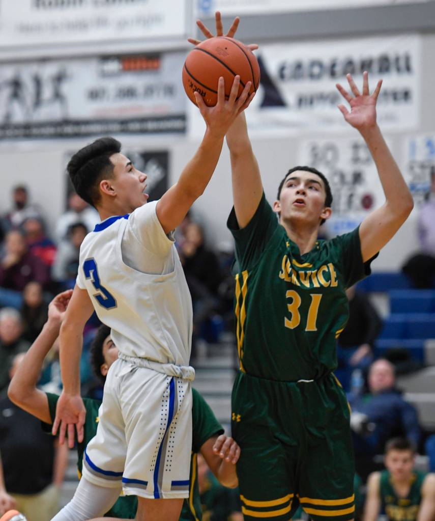 Thunder Mountains Bryson Echiverri lays the ball up around Services Zack Williamson at TMHS on Friday, Feb. 1, 2019. (Michael Penn | Juneau Empire)