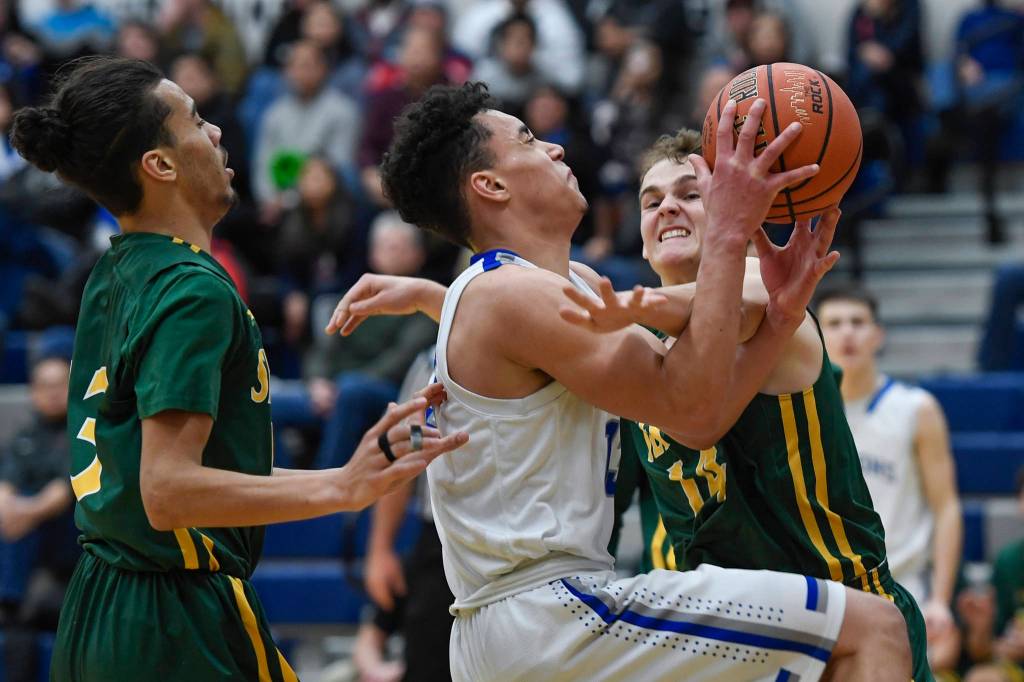 Thunder Mountains Kamron Falls, center, is fouled by Services Henry Hegleson at TMHS on Friday, Feb. 1, 2019. (Michael Penn | Juneau Empire)
