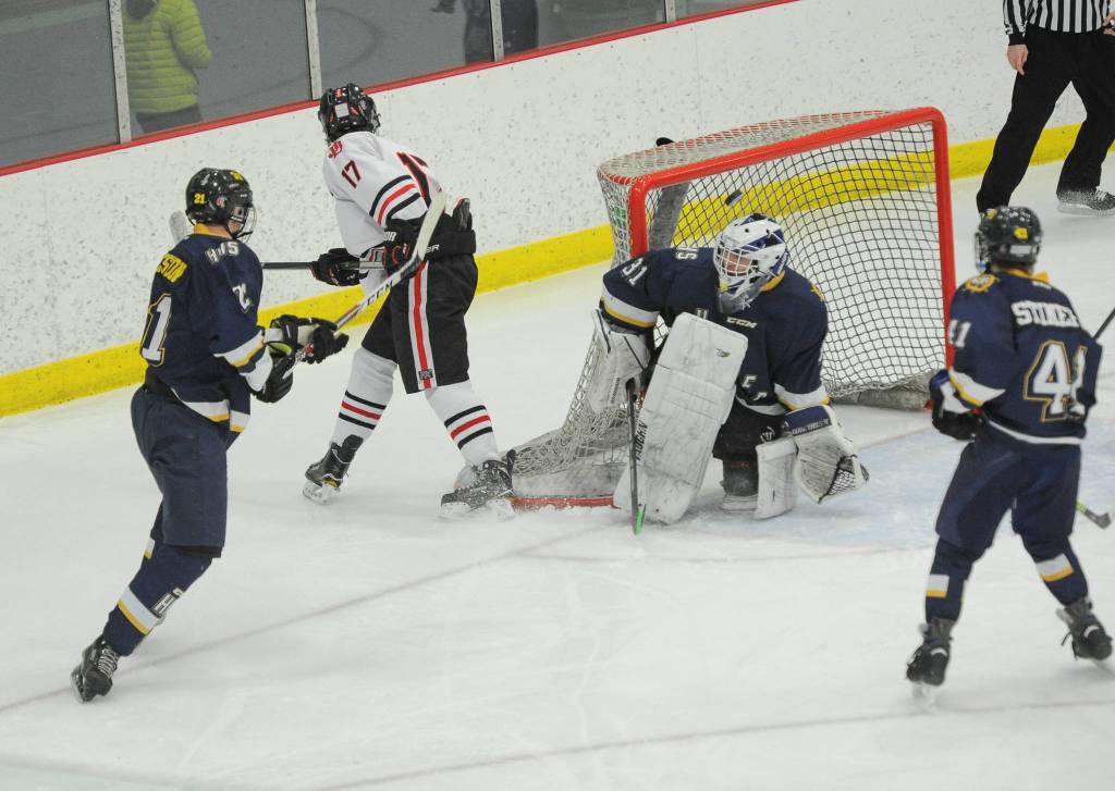 Homers Hunter Warren keeps the puck out of the net against the efforts of Juneaus Bill Bosse during the Crimson Bears 3-0 semifinal loss in the Division II state hockey championships Friday, Feb. 1, 2019. Looking on are Homers Tucker Weston (21) and Kazden Stineff. (Michael Dinneen | For the Juneau Empire)