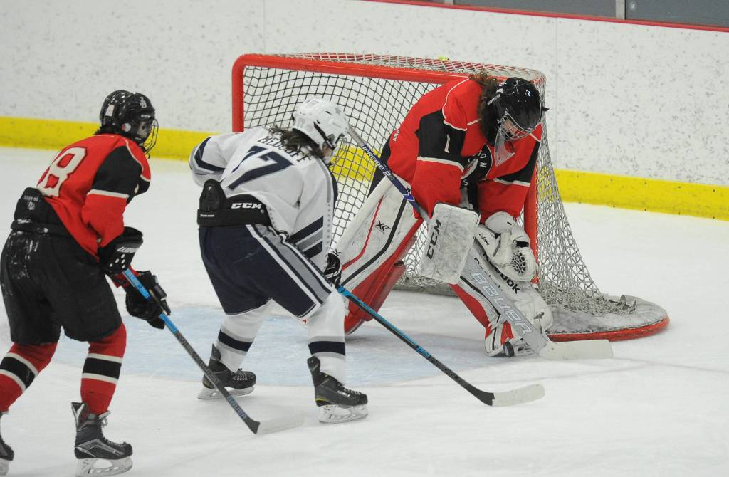 Juneau-Douglas Cody Mitchell makes a save against Soldotnas Wyatt Medcoff as Dalton Hoy looks on in the Division II state hockey championships third-place game on Saturday, Feb. 2, 2019. (Michael Dinneen | For the Juneau Empire)