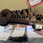 Mary Frances Fisher shows off a sign made by her husband, Alan. It was one of the items up for auction at a wine and beer tasting and silent auction benefiting Juneau Animal Rescue at the Westmark Baranof Hotel, Saturday, Feb. 9, 2019. (Ben Hohenstatt | Capital City Weekly)