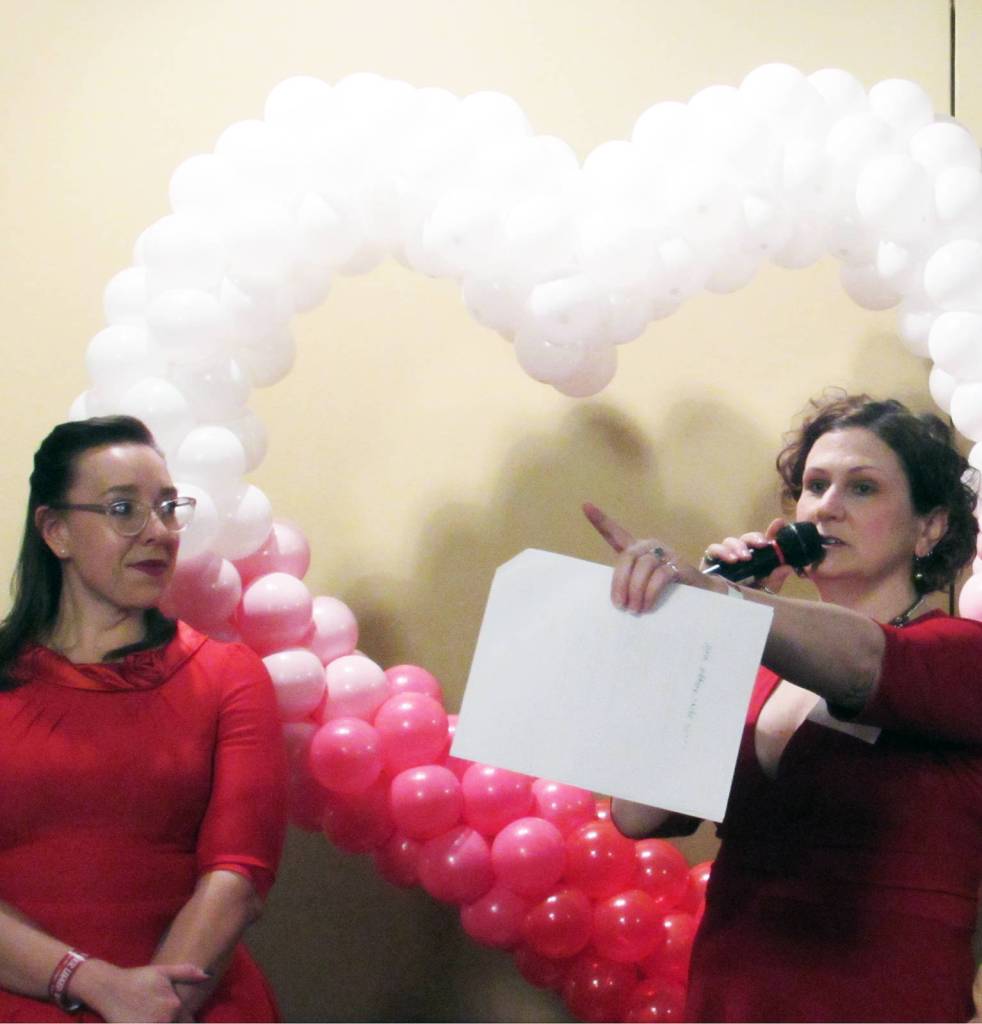 Amy Paige, Juneau Animal Rescue Board President, and Samantha Blankenship, Juneau Animal Rescue Executive Director, speak in front of a heart display at a wine and beer tasting and silent auction benefiting Juneau Animal Rescue at the Westmark Baranof Hotel, Saturday, Feb. 9, 2019. (Ben Hohenstatt | Capital City Weekly)