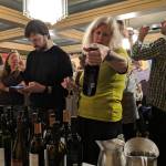 Kirsten Shelton considers a bottle of wine provided by Specialty Imports at a wine and beer tasting and silent auction benefiting Juneau Animal Rescue at the Westmark Baranof Hotel, Saturday, Feb. 9, 2019. (Ben Hohenstatt | Capital City Weekly)