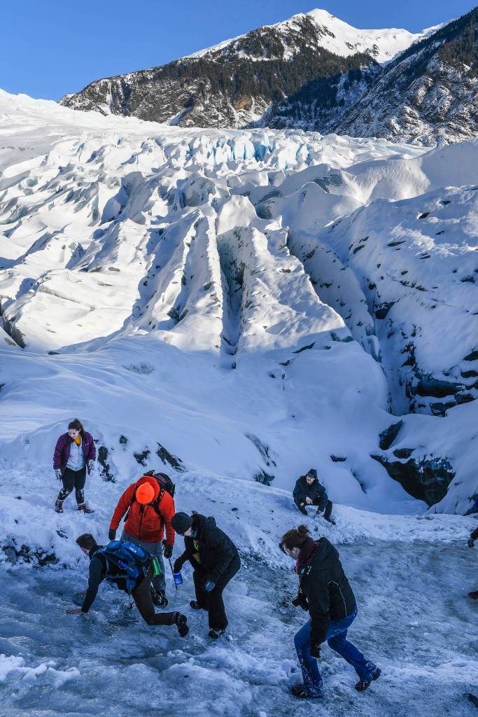 Explorers scamper over an icy patch on the way to an ice cave at the Mendenhall Glacier on Monday, Feb. 11, 2019. (Michael Penn | Juneau Empire)