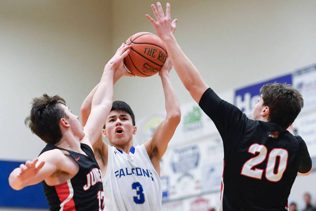Thunder Mountains Bryson Echiverri, center, shoots over Juneau-Douglas Brock McCormick, left, and Cooper Kriegmont at THMS on Friday, Feb. 15, 2019. TMHS won 69-59. (Michael Penn | Juneau Empire)