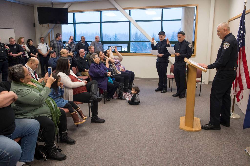 Chief of Police Ed Mercer swears in Jonah Hennings-Booth, of Eagle River, left, and Duain White, of Juneau, center, during a ceremony at the Juneau Police Department station on Thursday, Feb. 21, 2019. (Michael Penn | Juneau Empire)