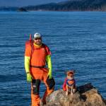 March 17, 2019: Brian Weed, a seasoned outdoor adventurer and founding member of Juneaus Hidden History group, is a colorful character! He knows that bright colors are an important safety consideration when out exploring remote areas around Juneau. Brian wears orange North Face softshell pants, chartreuse Carhartt long-sleeve shirt, orange Underground Explorer T-shirt, red ArcTeryx backpack, Sly Fox hat, Lowa boots, Kahtoola microspikes and climbing gear. Kat  his dog  wears her equally colorful Super Girl cape and Rex Specs polarized dog goggles.