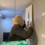 Laurie Craig hangs a work depicting an eagle feather during February before the spaces March 1 grand reopening. (Courtesy Photo | Juneau Artists Gallery)